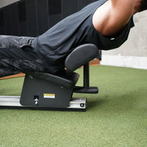 Machine in use by athlete showing the lower back support pad up close