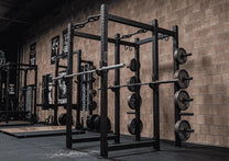 Full power rack shown in gym with optional Olympic bars and weight plates